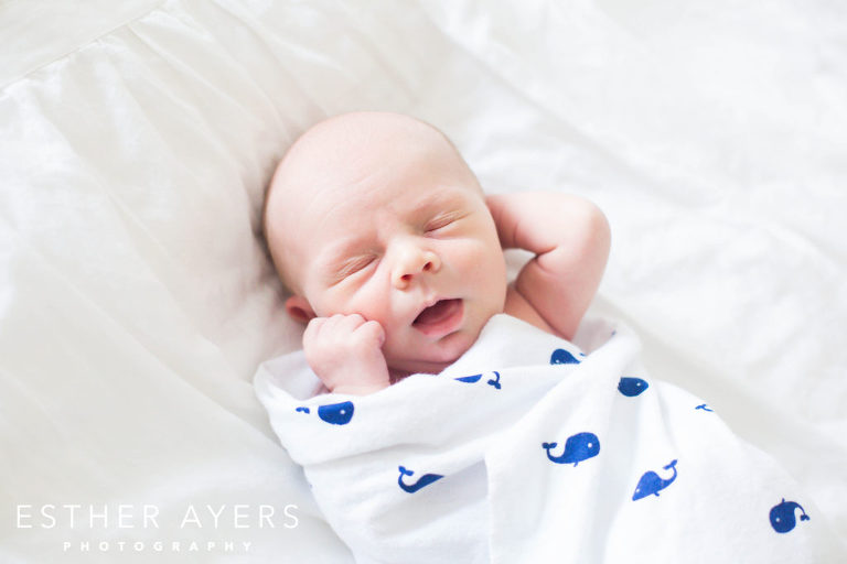 Newborn Baby Boy yawning on Bed in Master Bedroom