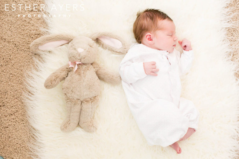 Newborn Baby Girl faux fur rug in nursery with stuffed animal bunny