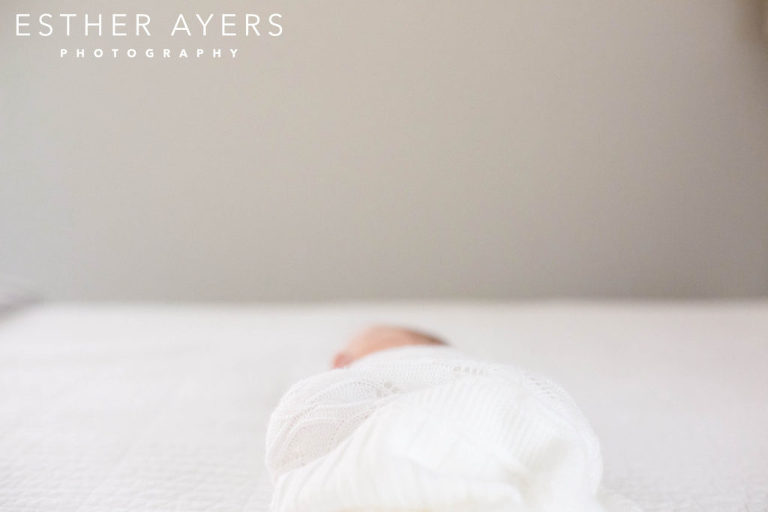 Newborn Baby Girl wrapped in blanket on Bed