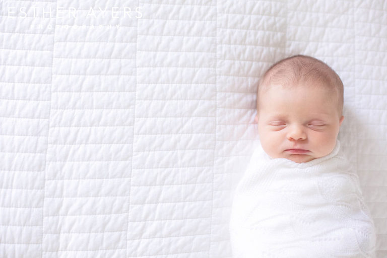Newborn Baby Girl wrapped in blanket on Bed