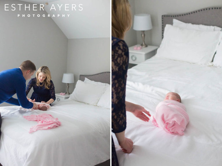 Mom and dad with newborn baby girl wrapped in a pink swaddle on a bed