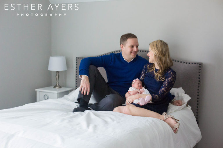 mom and dad looking at each other with newborn baby girl on bed