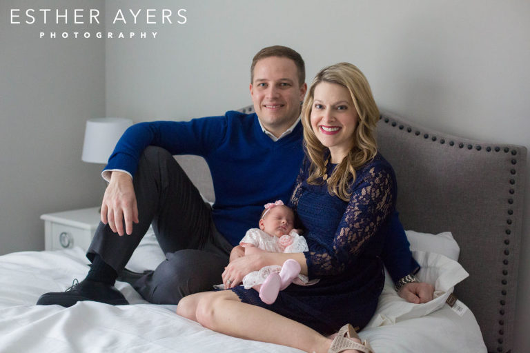 mom and dad with newborn baby girl on bed