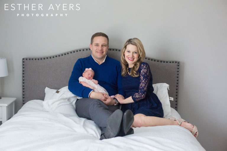 mom and dad with newborn baby girl on bed