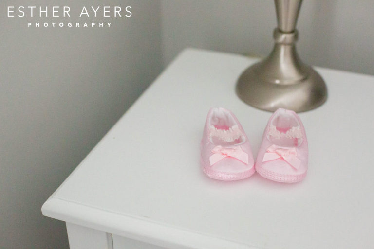 newborn baby girl pink shoes on bedside table with lamp