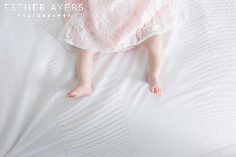 newborn baby girl in pink dress foot and toes closup
