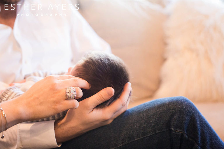 mom and dad hands holding newborn baby boy