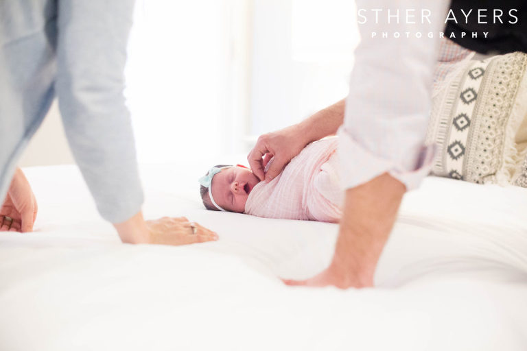newborn baby girl swaddled in a pink wrap on bed