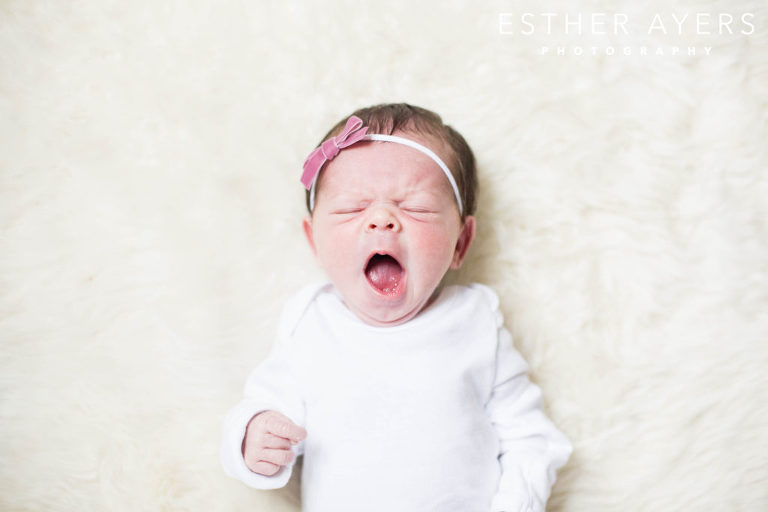 newborn baby girl yawning on faux fur rug